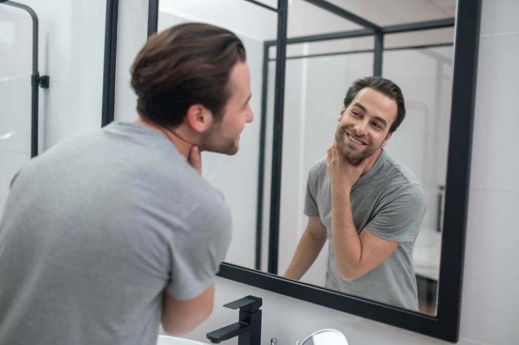 a man looking in the mirror is happy with his TED hair restoration treatment