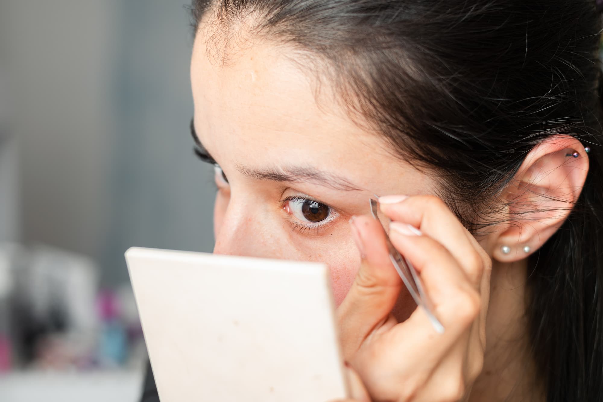 Close up of a girl plucking her unwanted eyebrow hairs